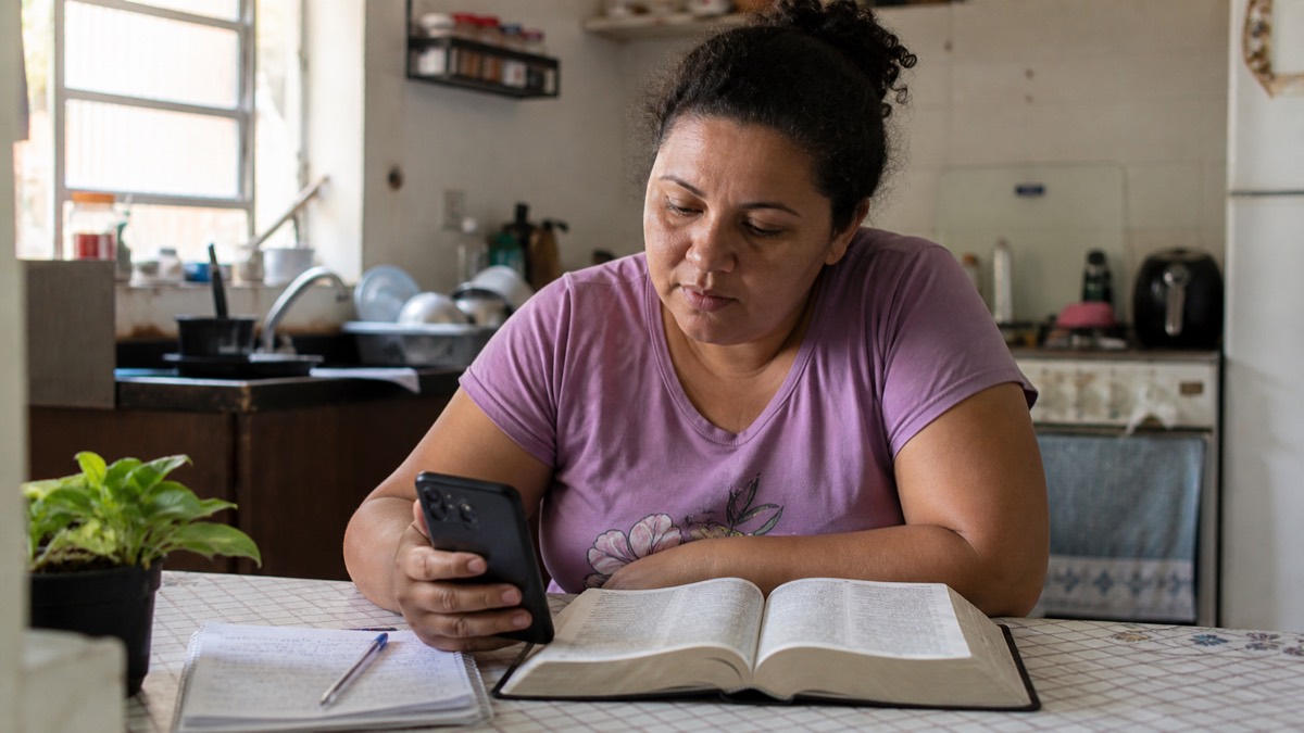 Cena ilustrativa de uma aluna estudando a Bíblia pelo celular